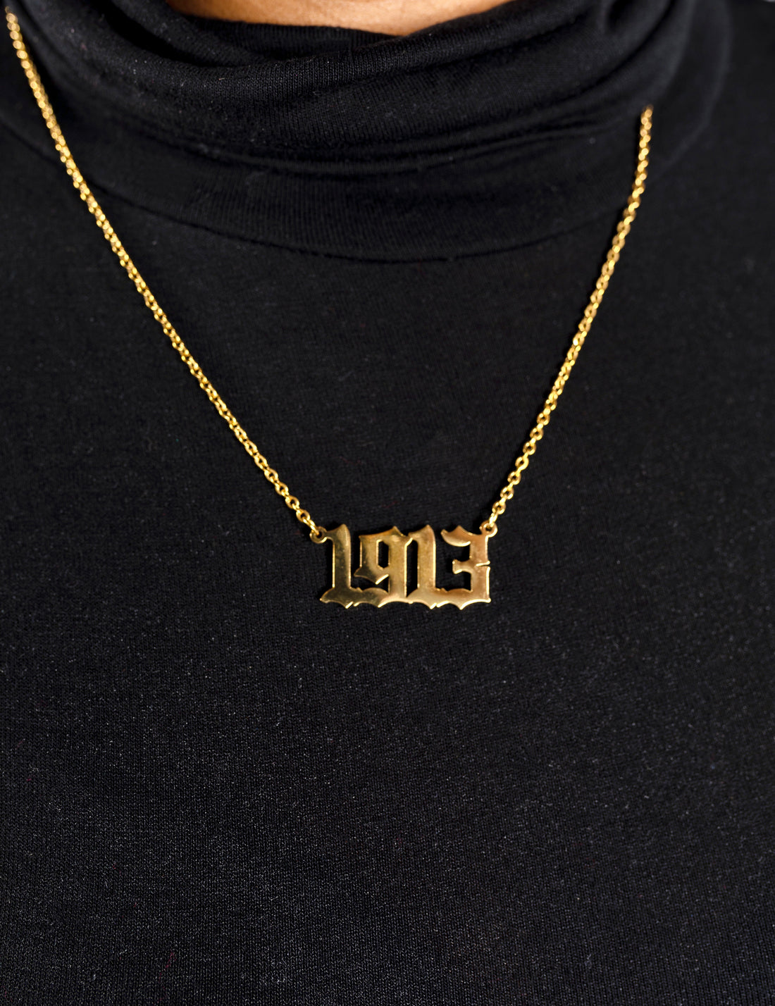 Silver necklace with a '1913' pendant on a beige background