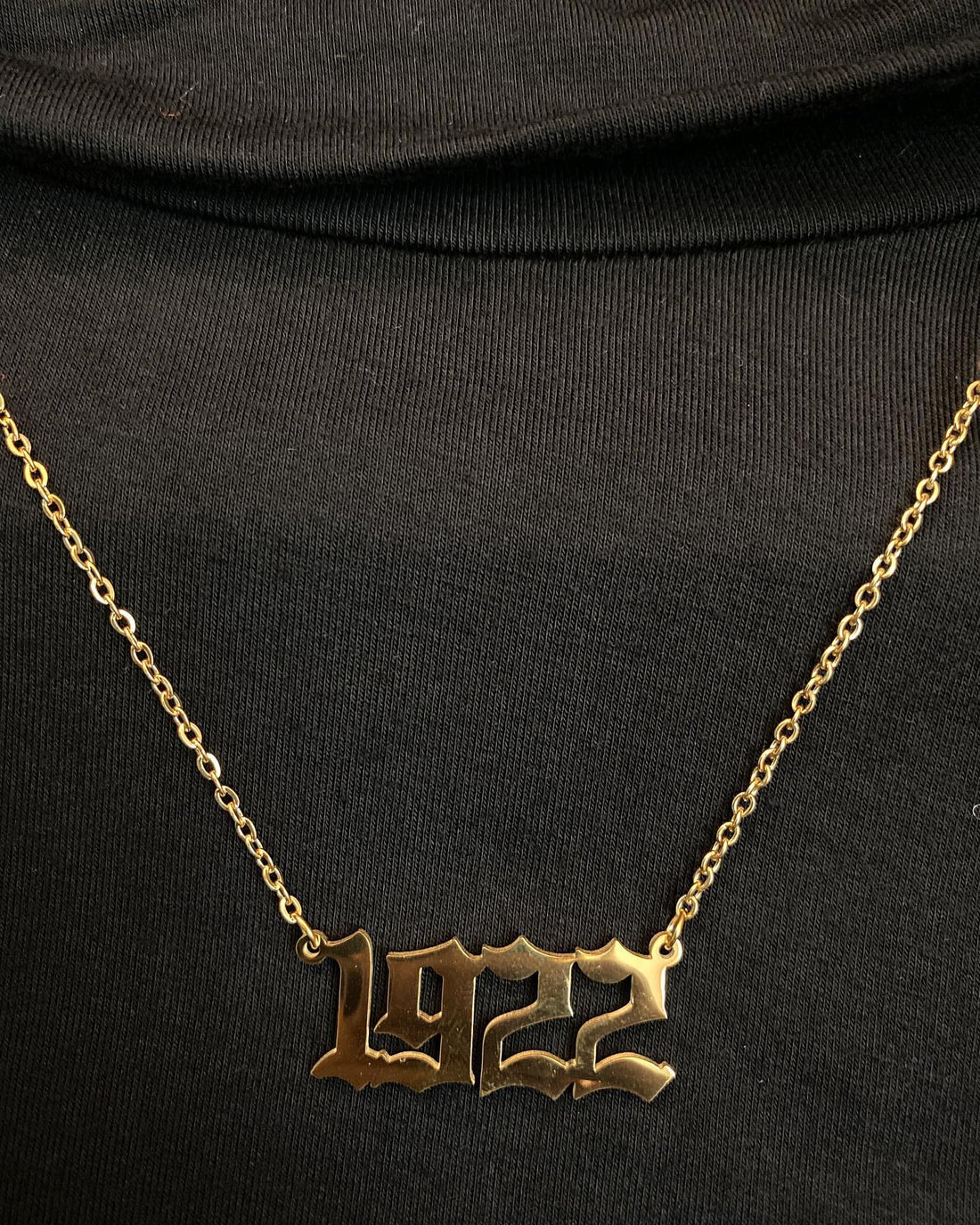Gold '1922' necklace on a black background