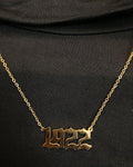Gold '1922' necklace on a black background