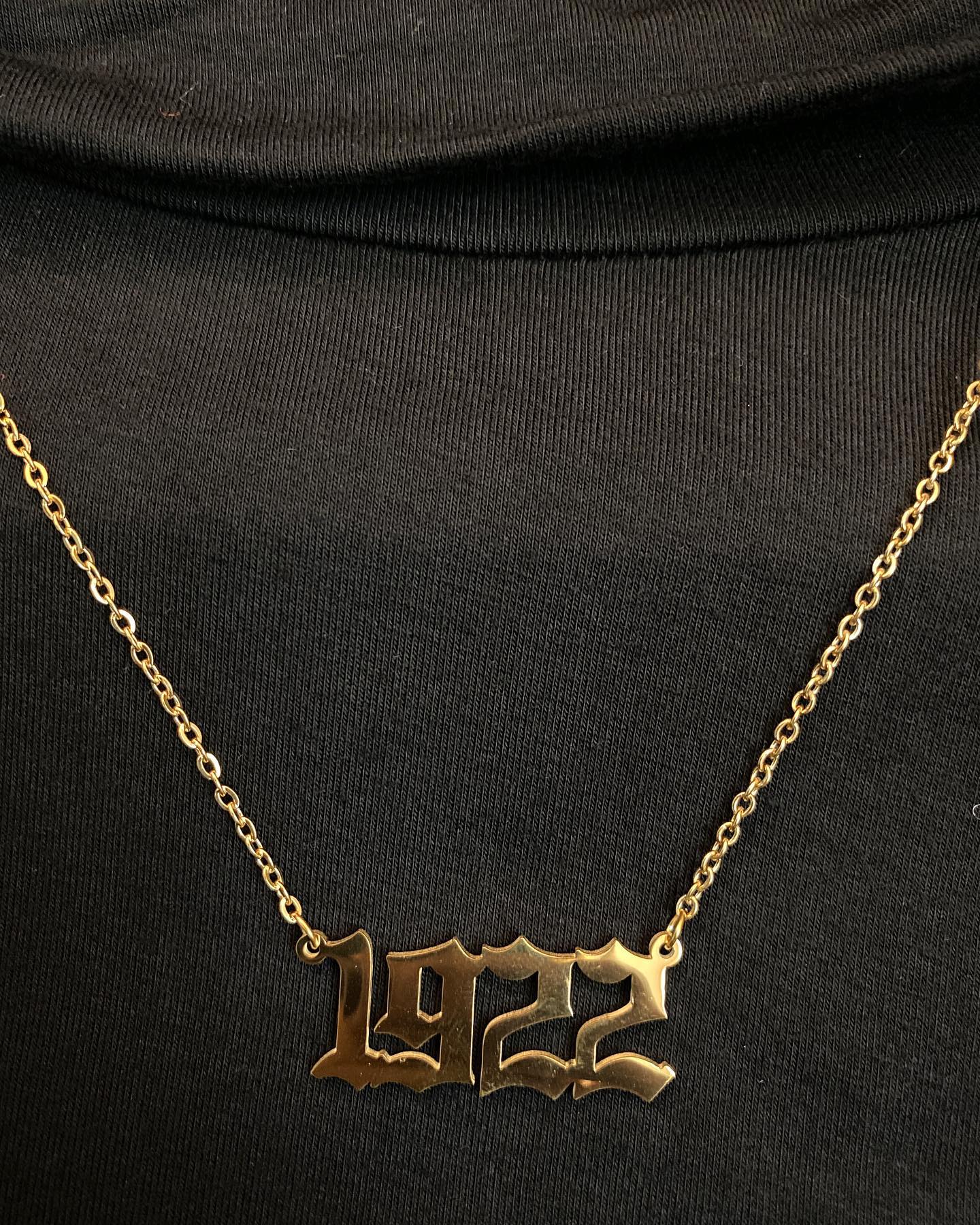 Gold '1922' necklace on a black background