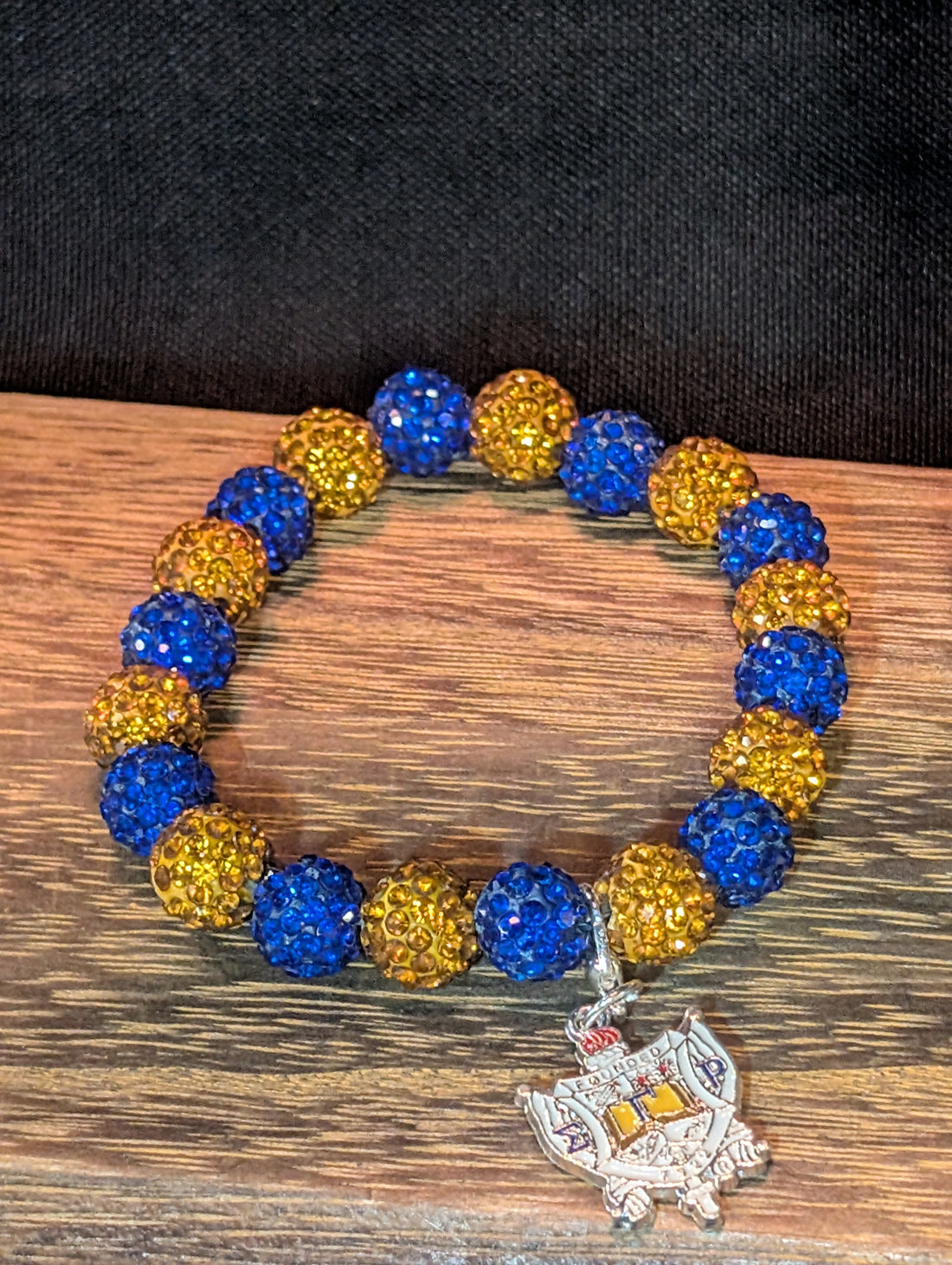 Bracelet with blue and yellow beads and a silver charm on a black background
