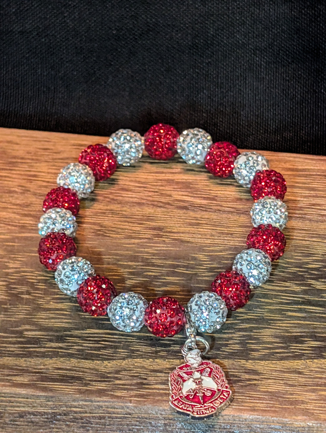 Bracelet with red and white beads and a pendant on a black background