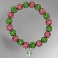 Bracelet with pink and green beads and a silver charm on a black background