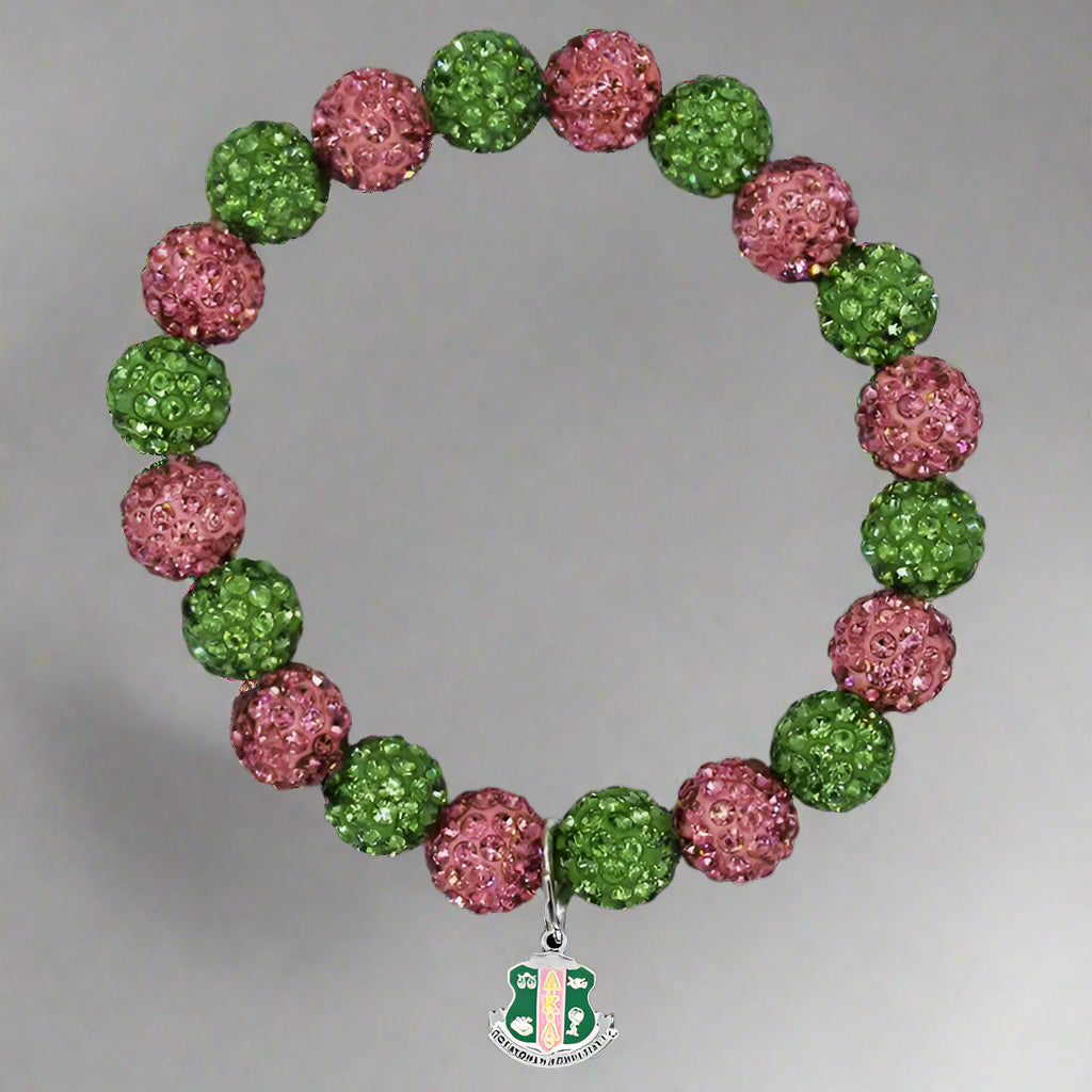 Bracelet with pink and green beads and a silver charm on a black background