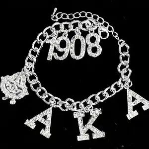 Silver bracelet with '1908' and 'AKA' charms on a black background
