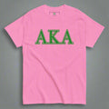 Pink t-shirt with 'AKA' in green letters on a gray background
