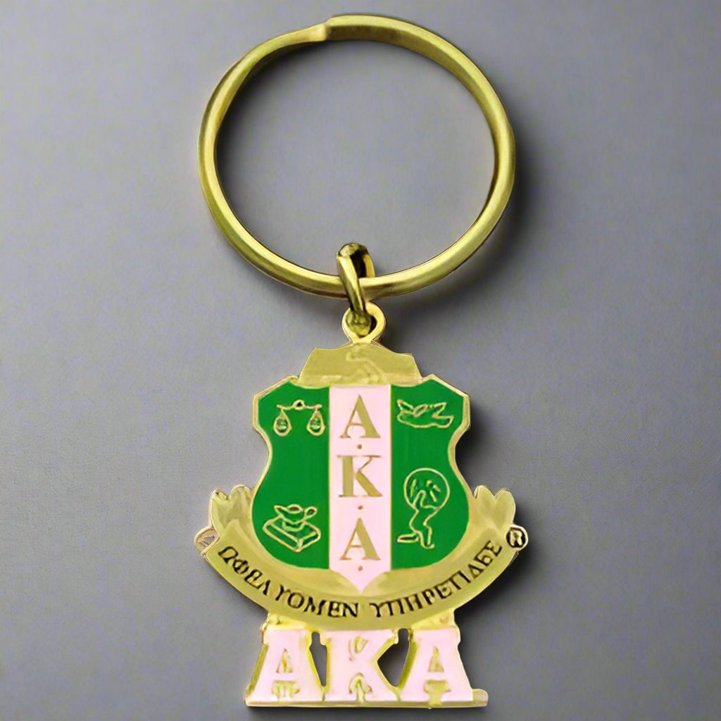 Gold keychain with green and gold emblem featuring 'AKA' letters on a black background