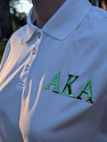 White polo shirt with green 'AKA' letters on left chest
