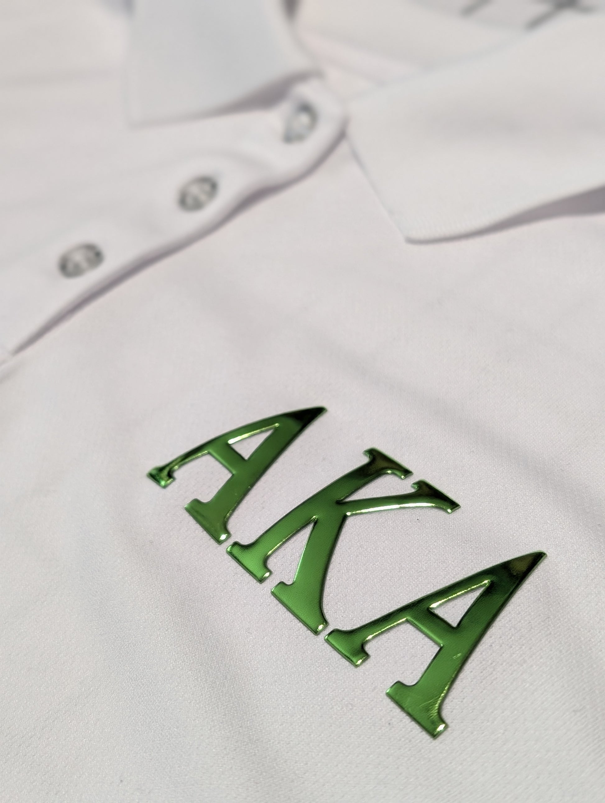 white polo with green metallic letters aka on the left chest