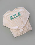 Light pink sweatshirt with 'AKA' in green letters on a gray background