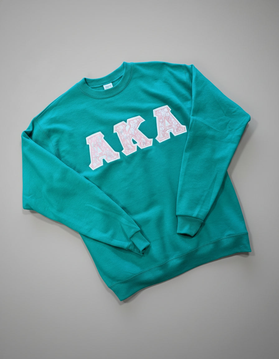 Green sweatshirt with pink 'AKA' text on a gray background