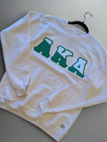 light pink sweatshirt with 'AKA' in green letters