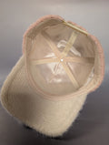 cream satin lined underside of a pink fur hat with a cream bill