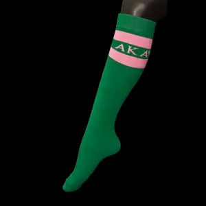 Green knee-high sock with pink stripes and 'AKA' lettering on a black background
