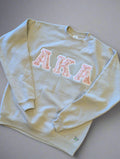 cream sweatshirt with pink 'AKA' letters 