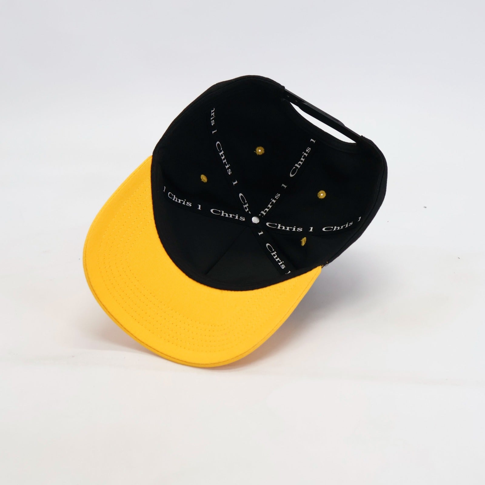 Black and yellow cap with 'Chris' branding on inner cap