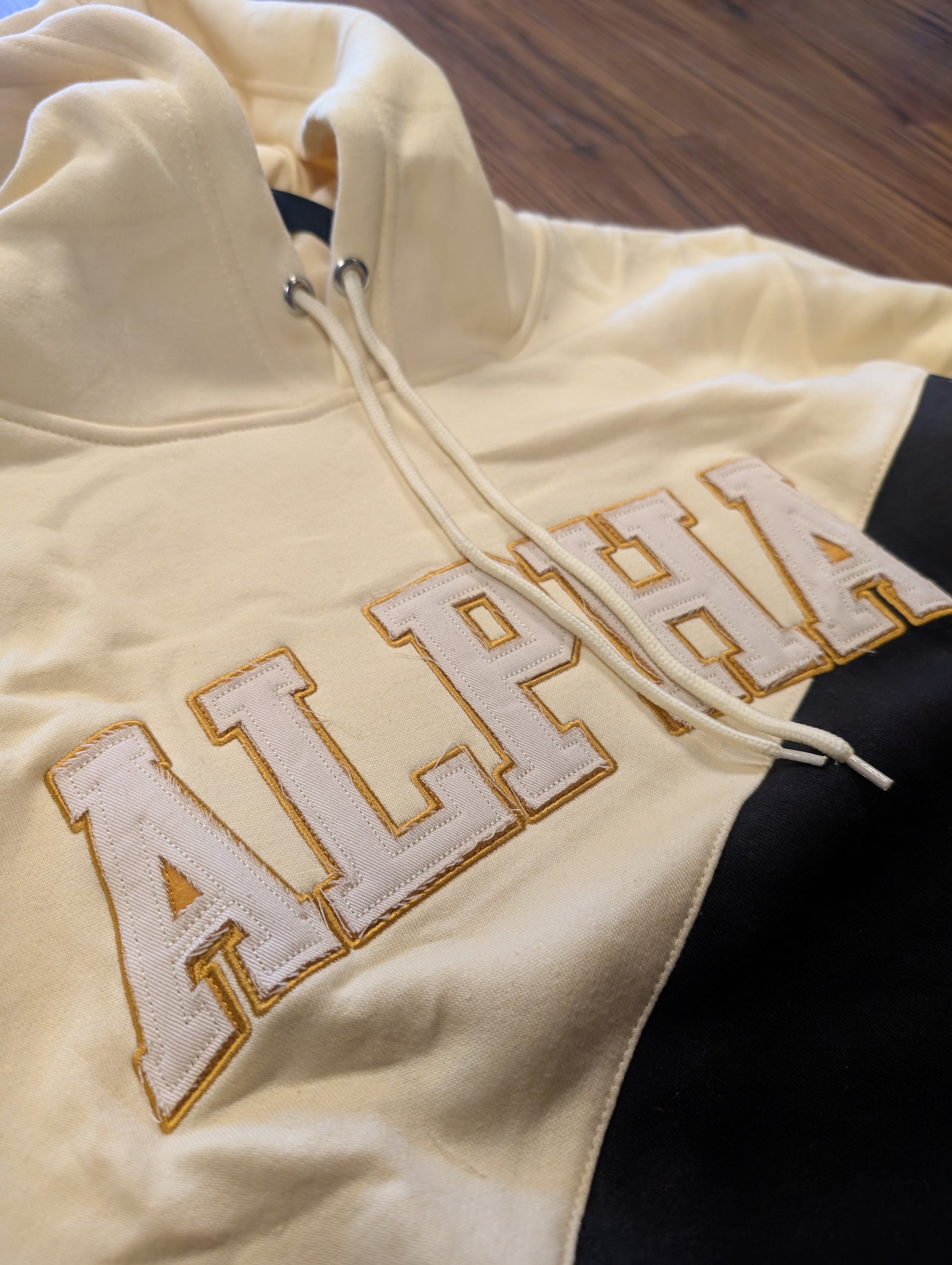 black and cream hoodie with 'ALPHA' embroidered on it