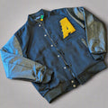 Black varsity jacket with a yellow letter 'A' on a wooden surface