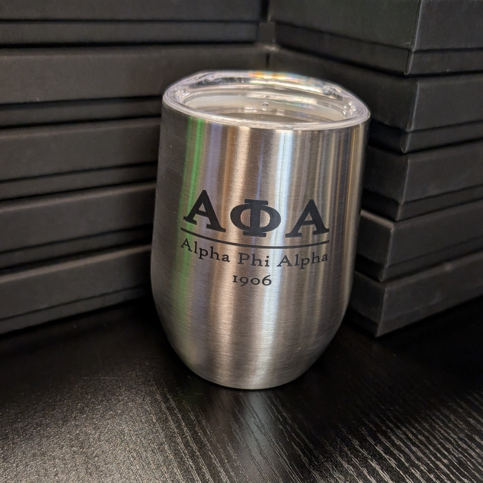 Silver tumbler with Alpha Phi Alpha logo on a dark surface
