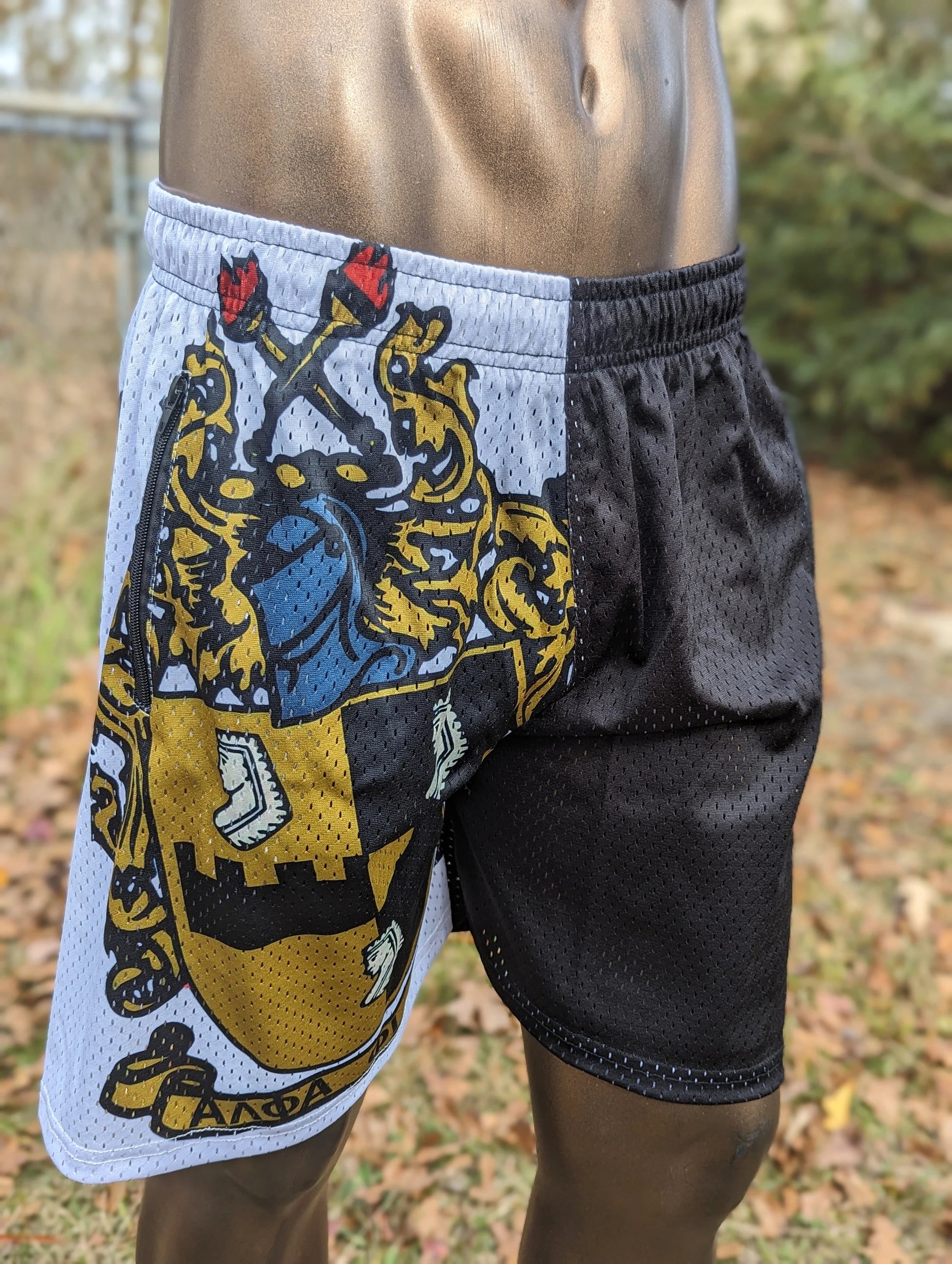 Shorts with a detailed emblem design on a white background, worn outdoors.
