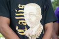 Person wearing a black t-shirt with a graphic design of a face made from text and the word 'Alpha'.