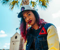 Woman wearing a denim varsity jacket with a red delta design outdoors