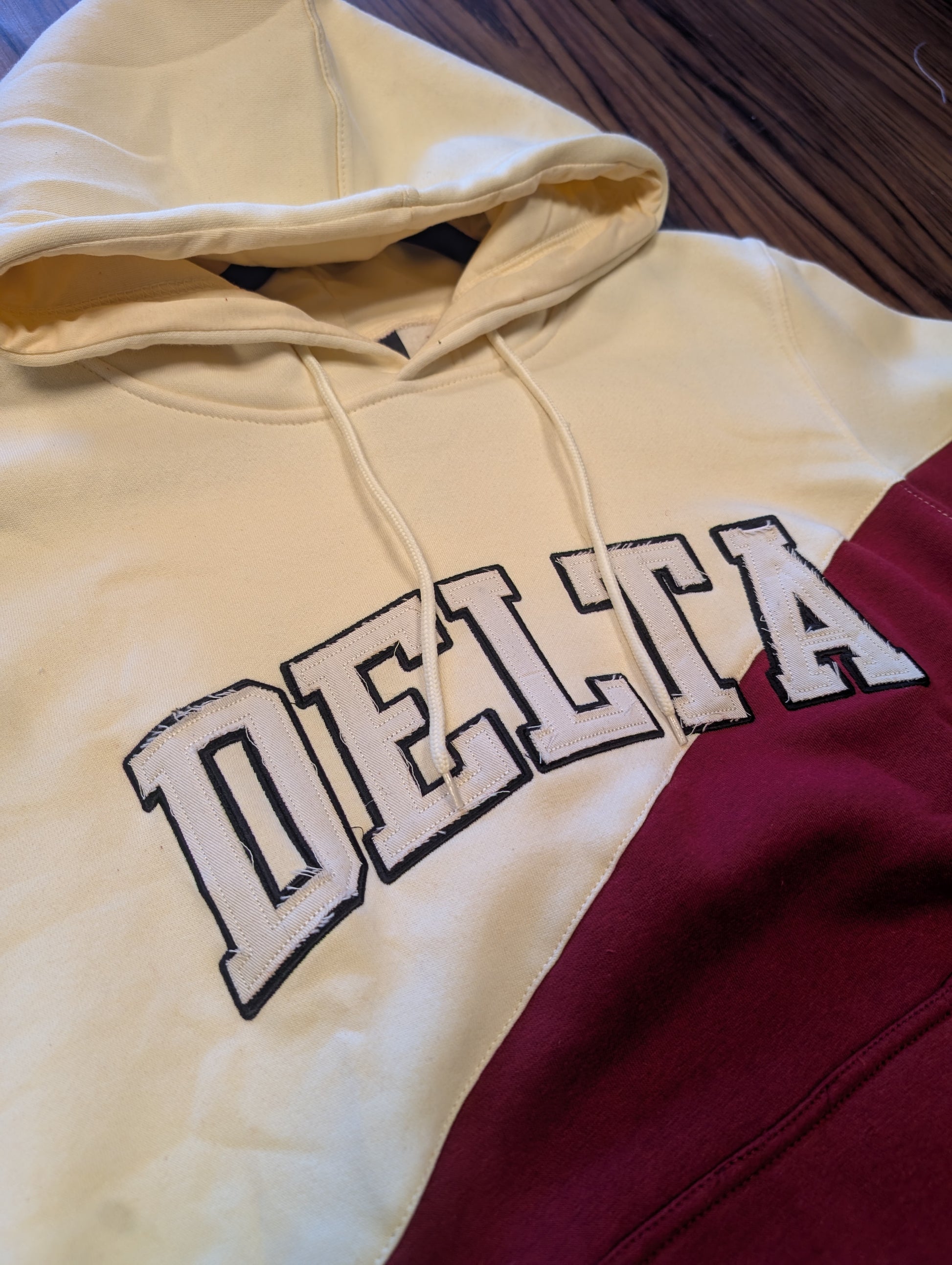 crimson and cream hoodie with "delta" on the chest