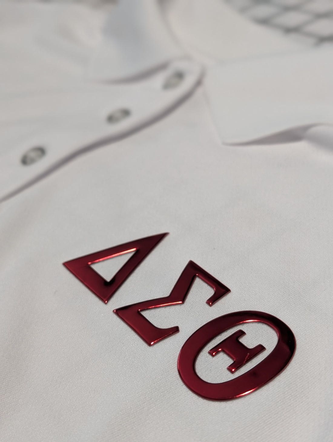 white polo with red greek letters delta sigma theta on left chest