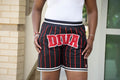 Person wearing black shorts with red pinstripes and 'DIVA' text, standing outdoors.