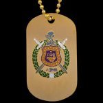 Gold dog tag with emblem and green stones on a chain