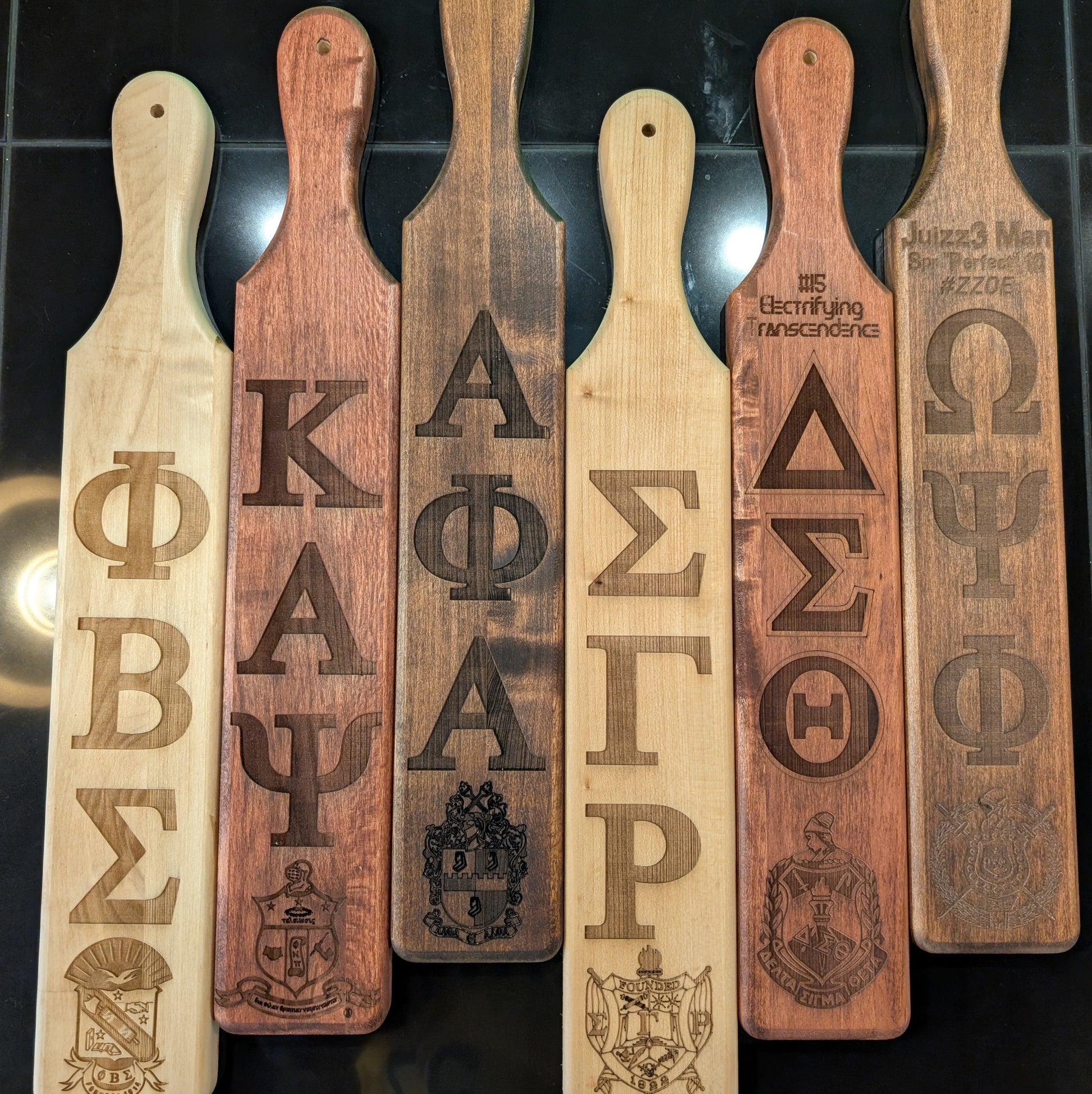 Set of wooden paddles with engraved symbols and logos on a dark background