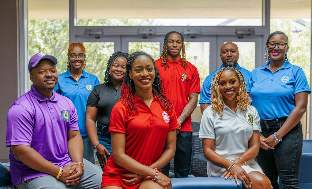Group of people in a professional setting, wearing colorful shirts.