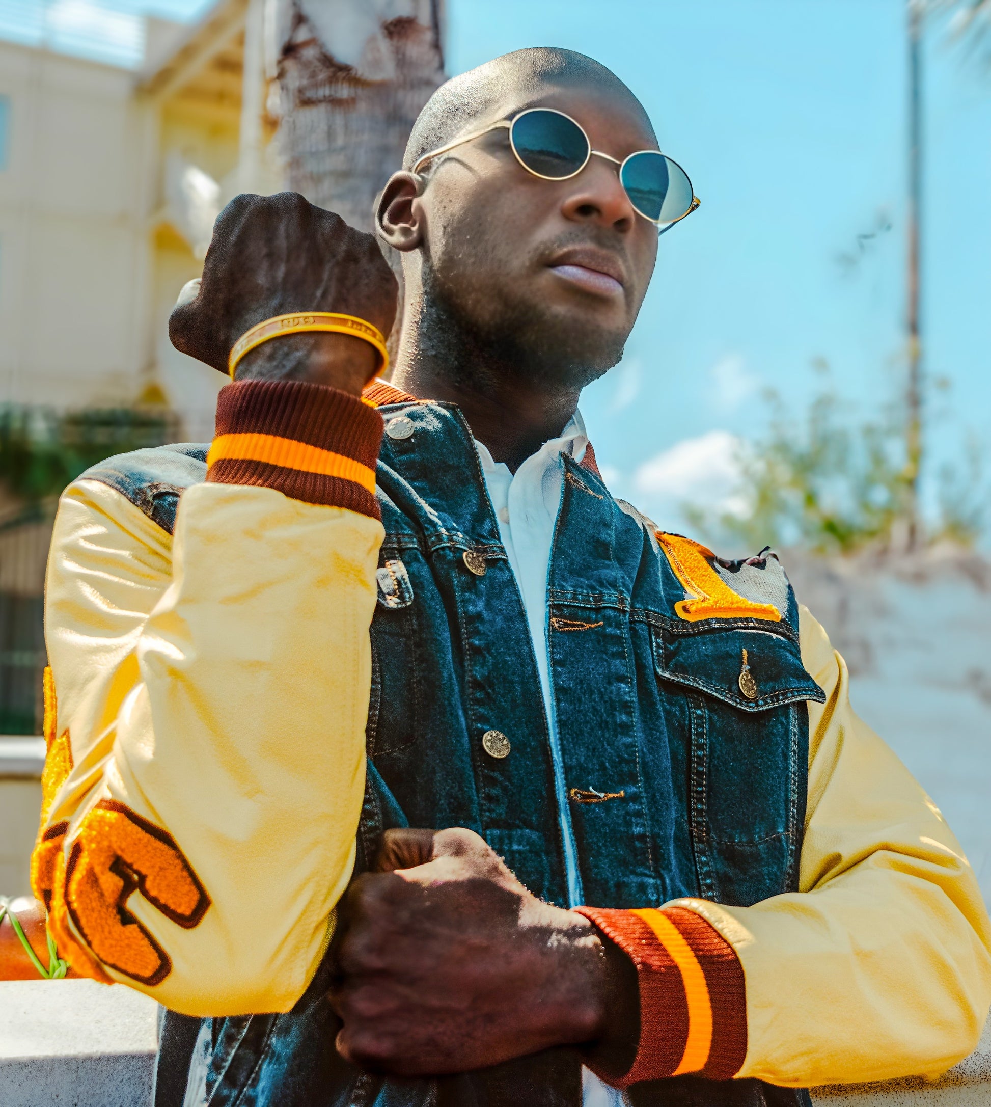 Man wearing an iota phi theta denim varsity jacket with chenille accents.