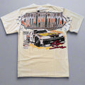 Beige t-shirt with a graphic of a race car and text on a wooden surface