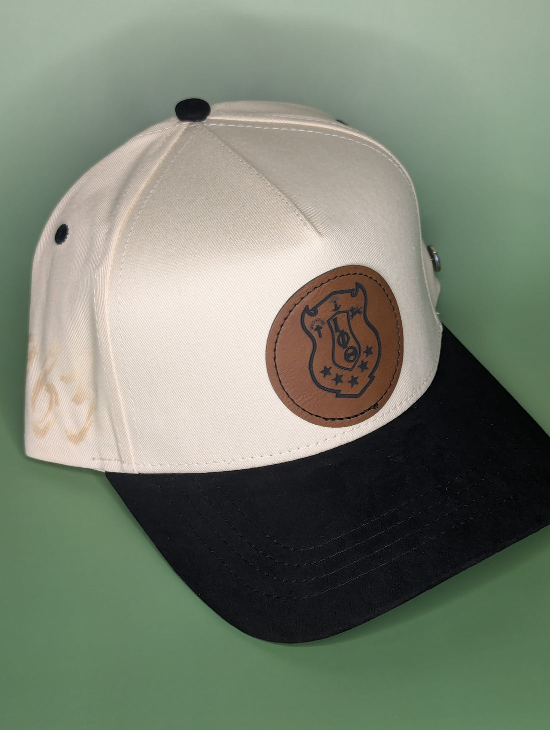 Two baseball caps with leather patches and '1963 Iota ' text on a brown background.