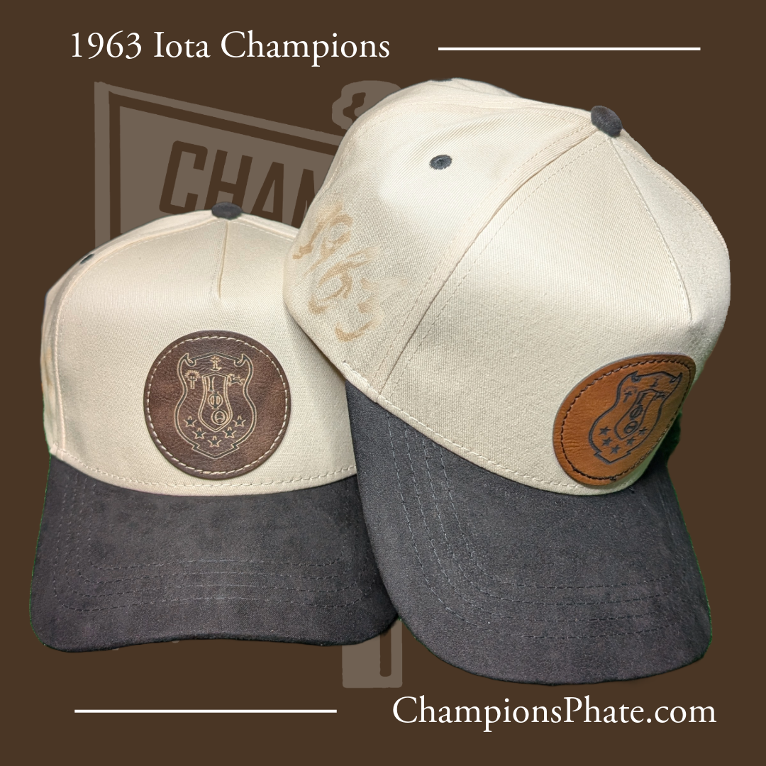 Two baseball caps with leather patches and '1963 Iota ' text on a brown background.