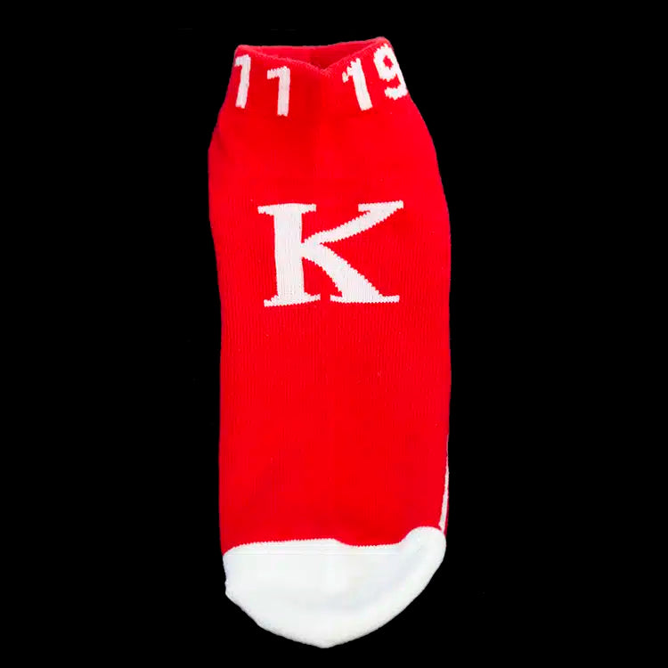 Red sock with white letter 'K' and numbers on a black background