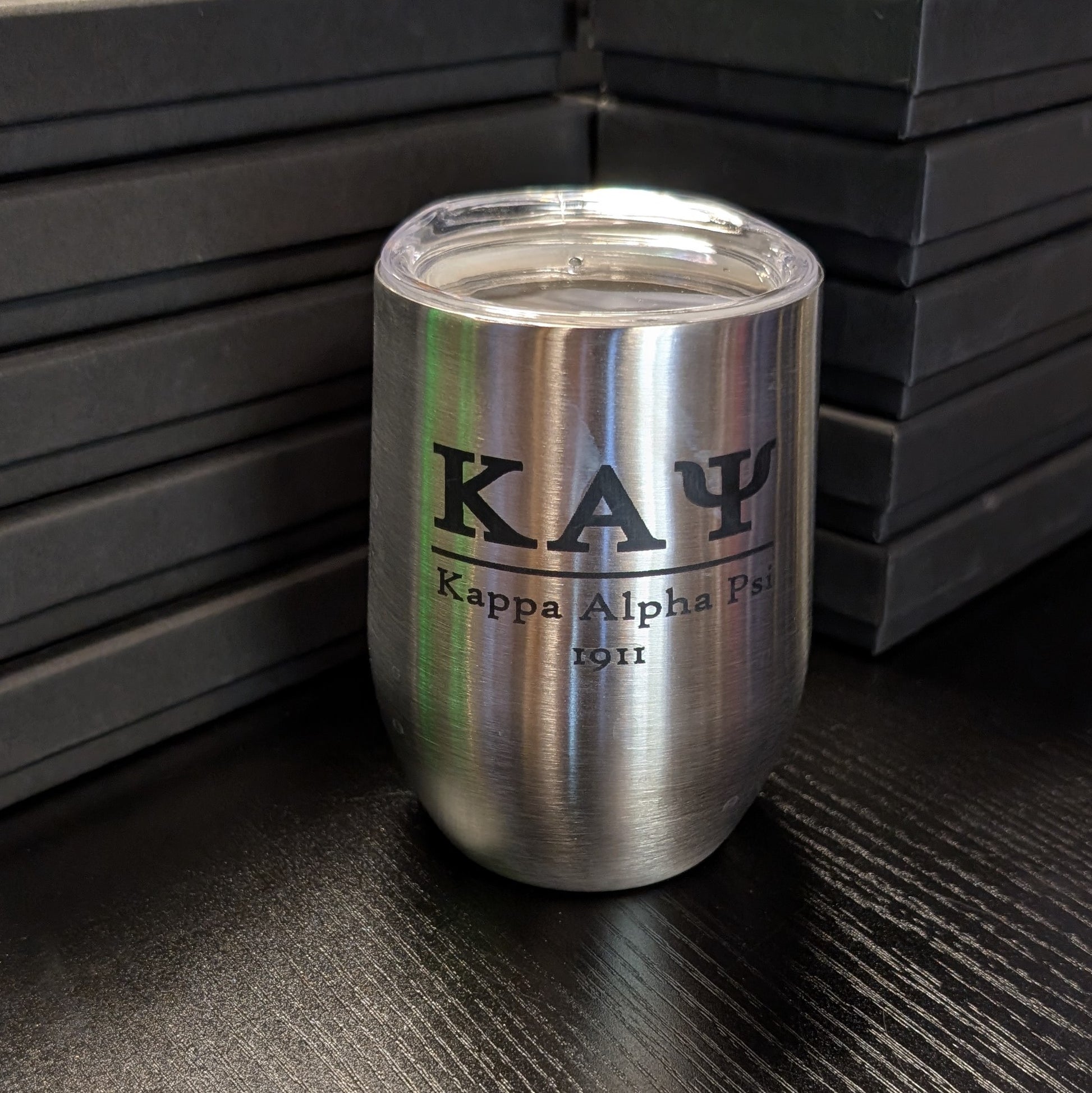 Silver tumbler with 'Kappa Alpha Psi' text on a dark surface