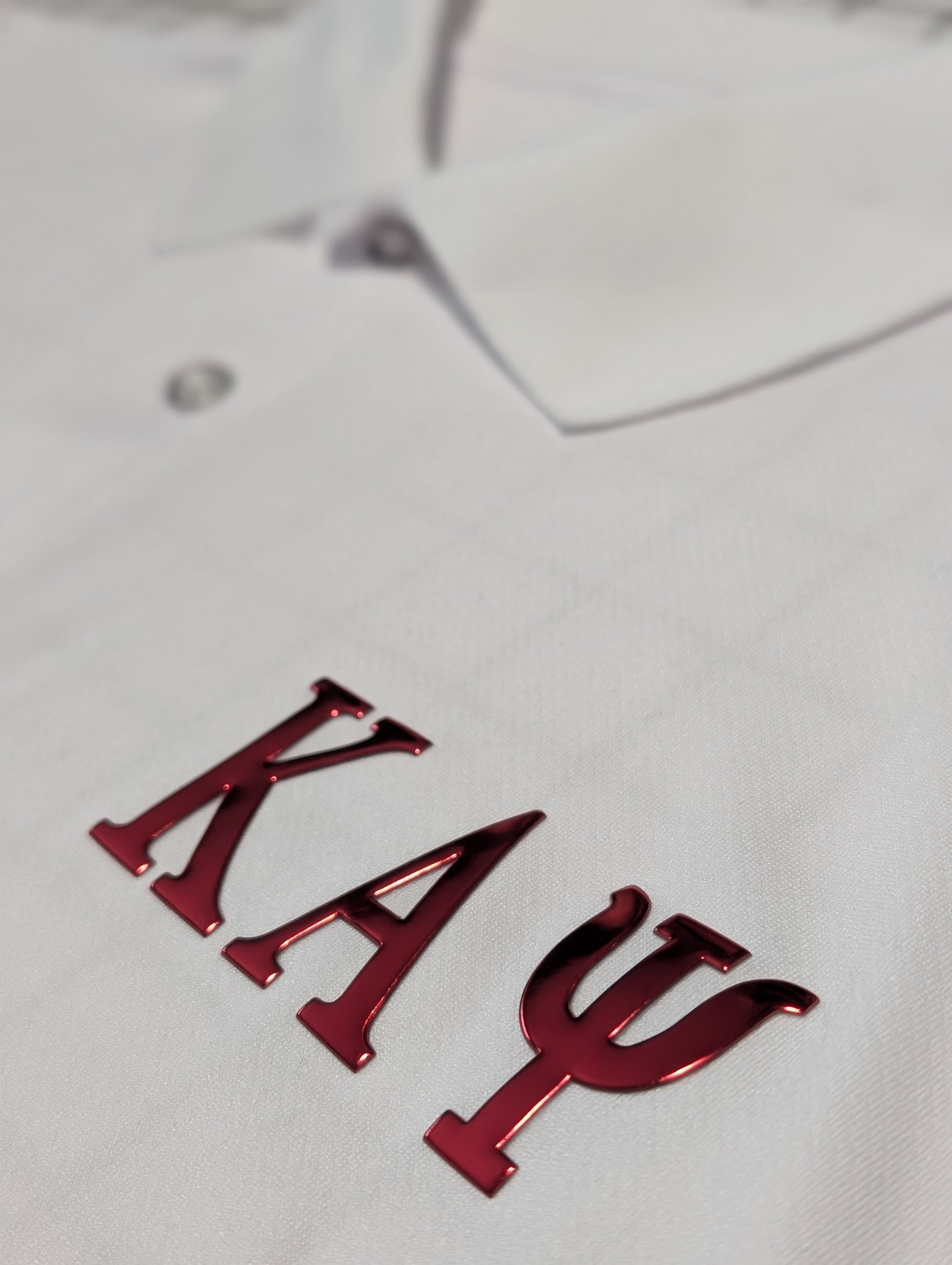 white polo with red greek letters kappa alpha psi on left chest