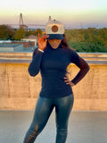 Person wearing a navy long-sleeve top and black leggings with a cap outdoors.