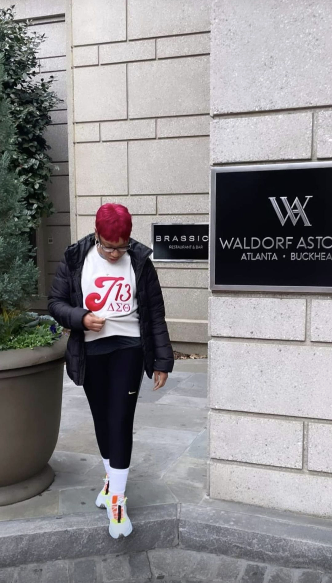 Person wearing a white sweatshirt with red and black text and symbols