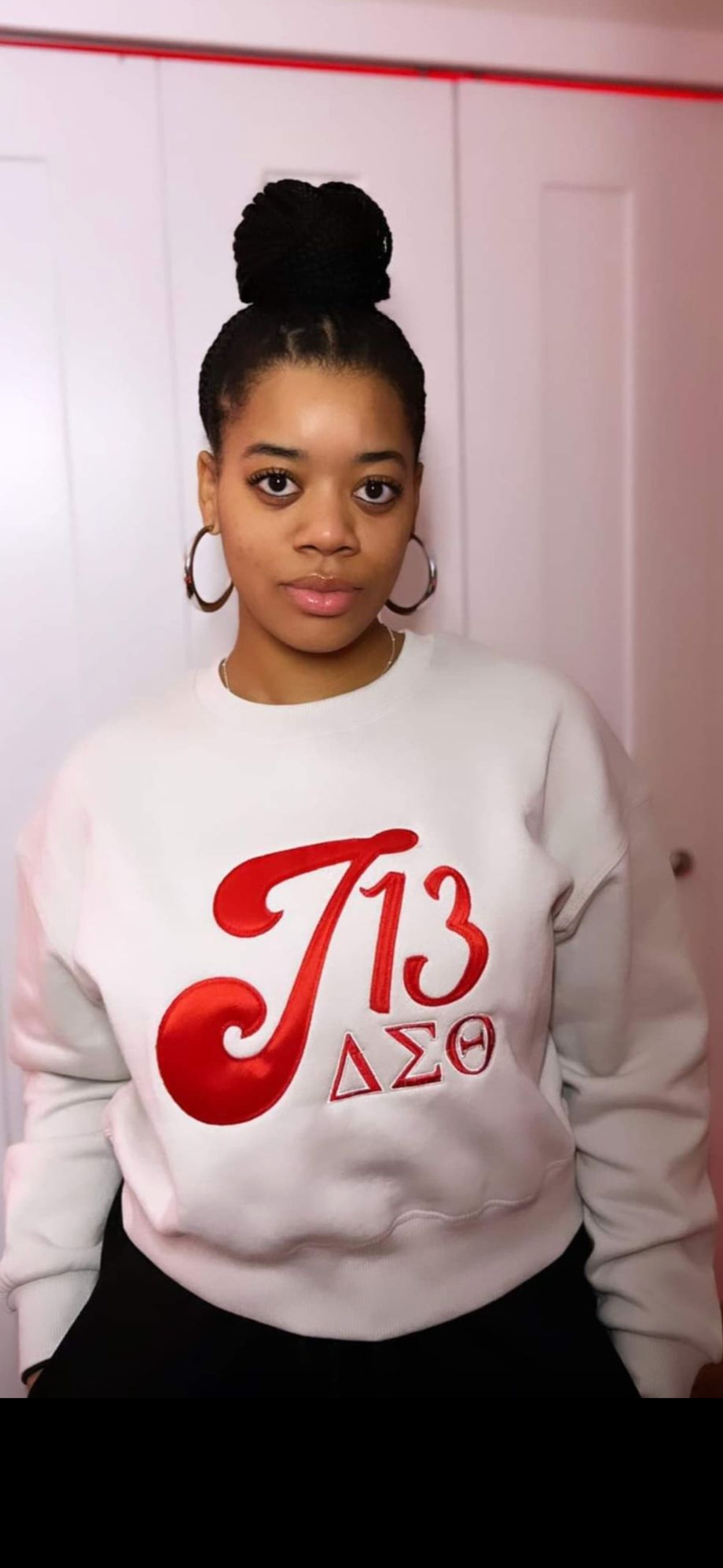 Person wearing a white sweatshirt with red and black text and symbols