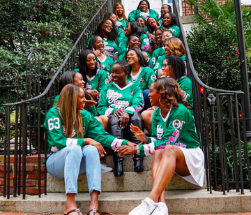 Group of women in green sweaters sitting on steps outdoors