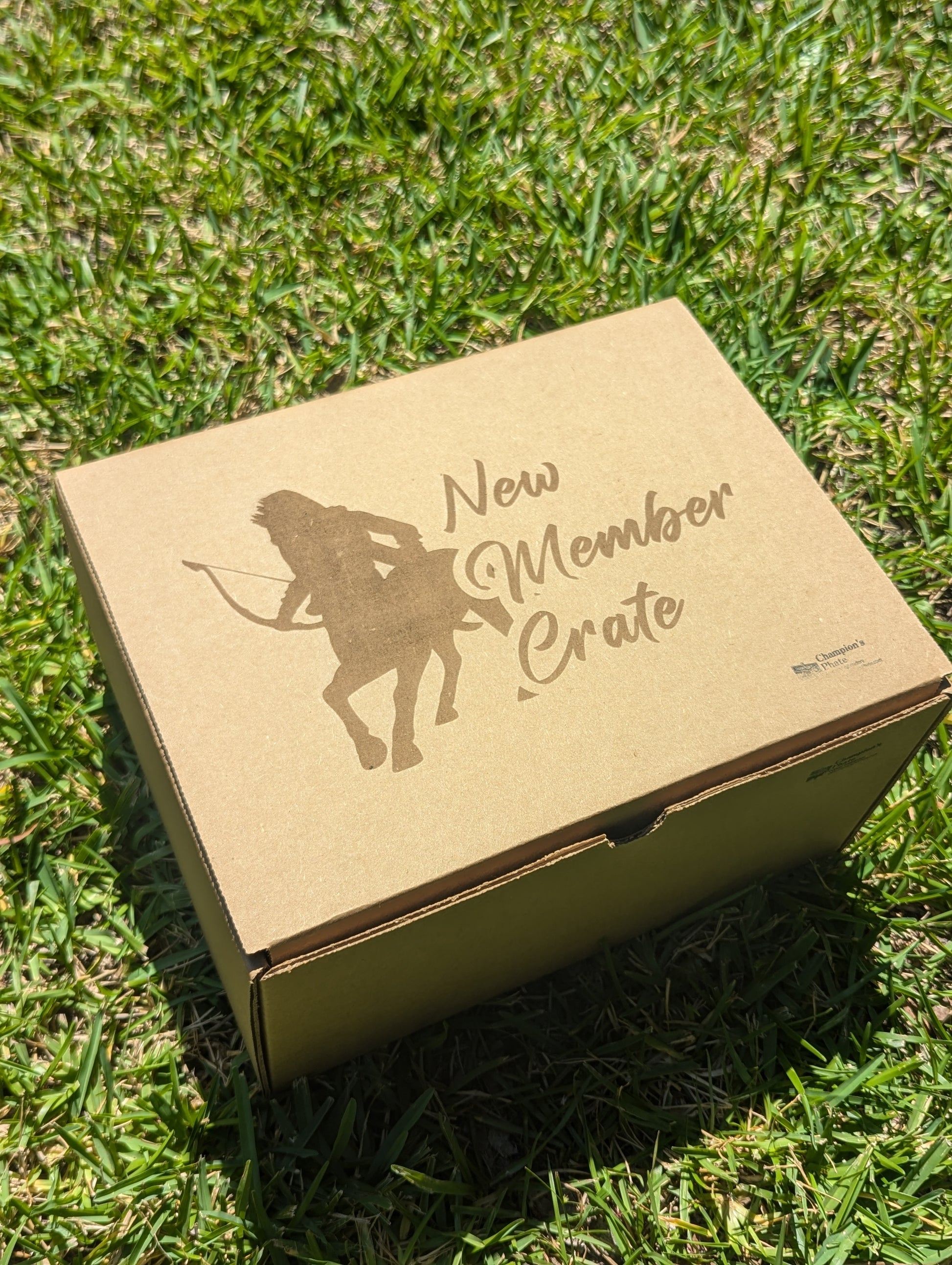 Cardboard box labeled 'New Member Crate' on grass