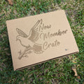 A cardboard gift box with 'NEW MEMBER CRATE' printed on it, featuring an embossed design of a dove perched on a branch 