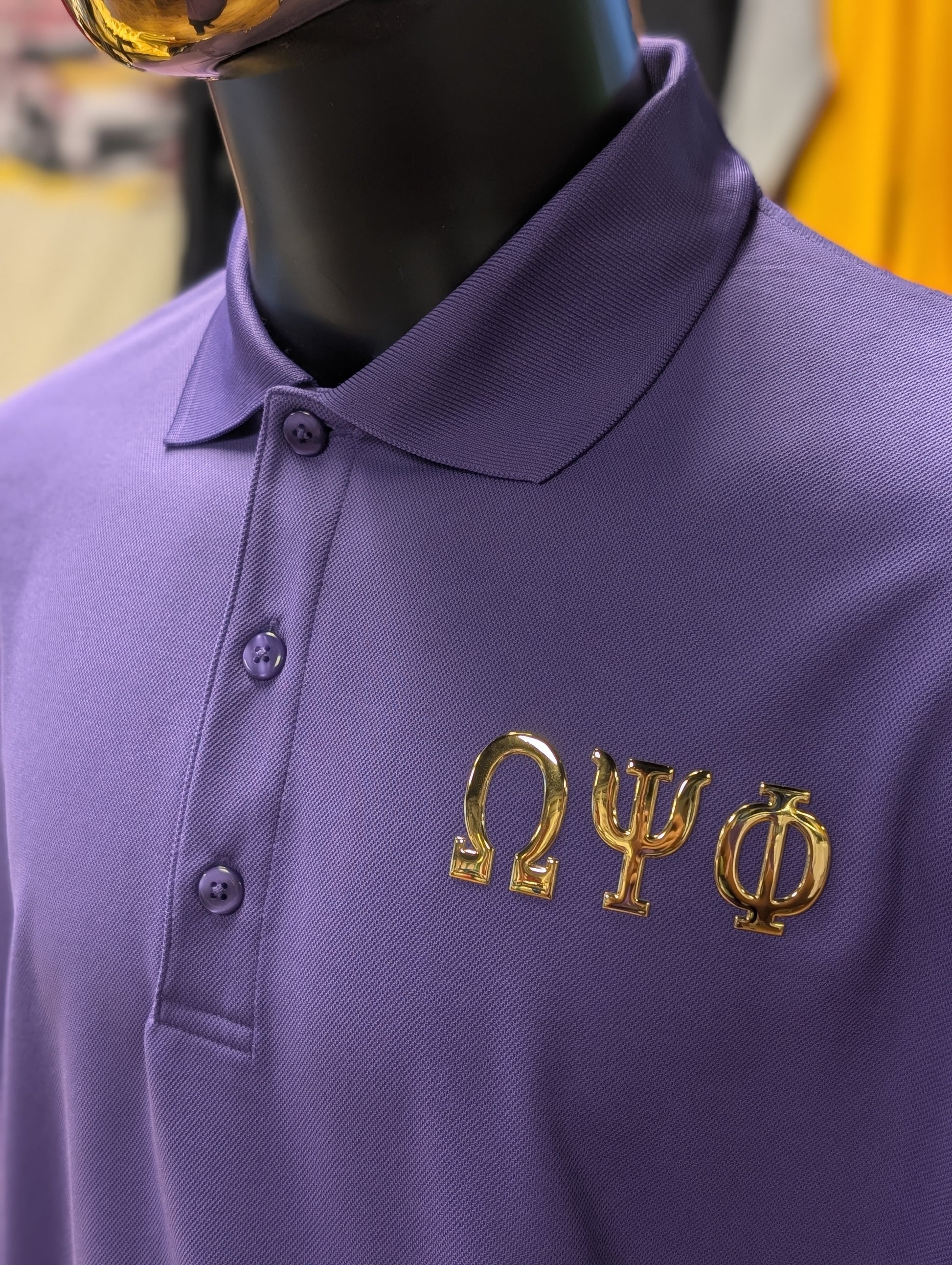 Purple polo shirt with gold greek letters omega psi phi on left chest