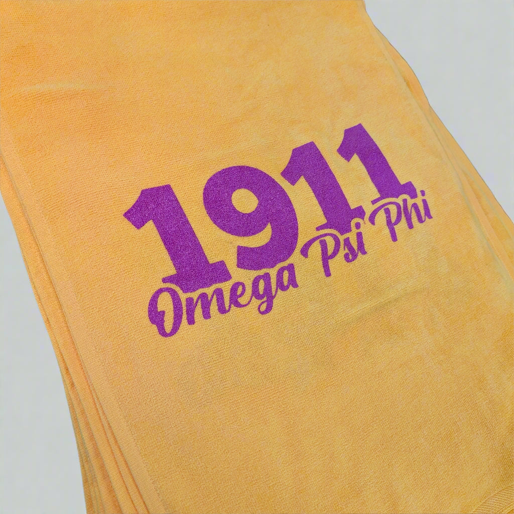 Yellow towel with purple '1911 Omega Psi Phi' text on a black background
