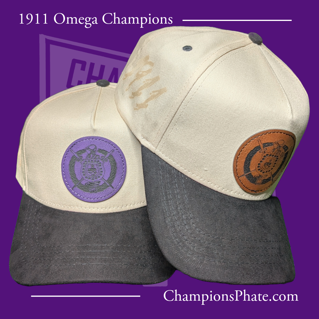 Two A-frame caps with suede brims, one primarily off-white and the other with a gray bill, featuring pins and an engraved design on the front.