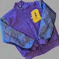 Purple varsity jacket with a yellow 'Q' on a wooden surface