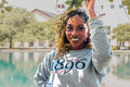 Person wearing a gray sweatshirt with '1896' and 'South Carolina' text, holding leaves by a pool.